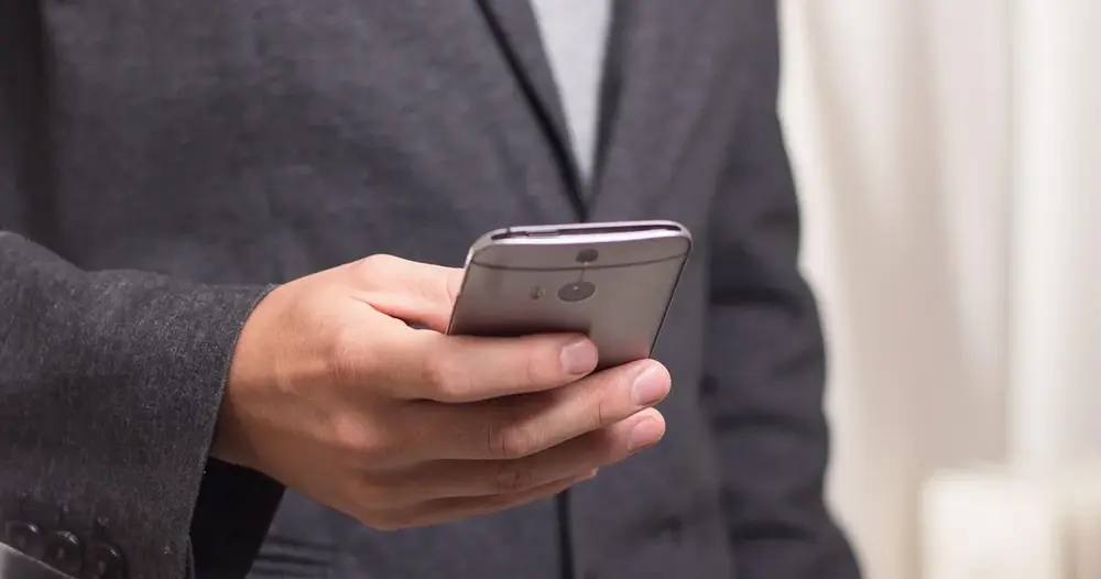 Mão segurando um smartphone, cena de quem copia letras diferentes para a bio do perfil
