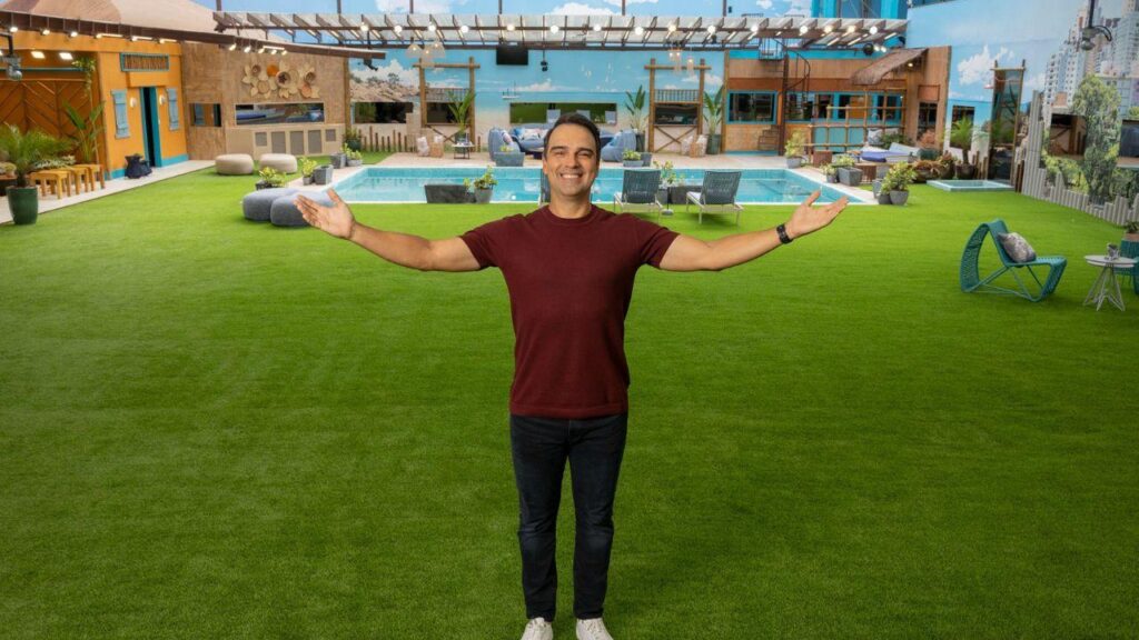 Signos que podem enfrentar conflitos no BBB Mostra Tadeu Schimidt no gramado do BBB. Homem branco, cabelo preto curto, camiseta vermelha e calça preta.